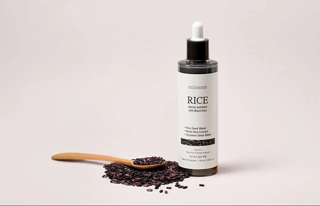 Mixsoon Black Rice Peeling Shot standing by a wooden spoon full of black rice