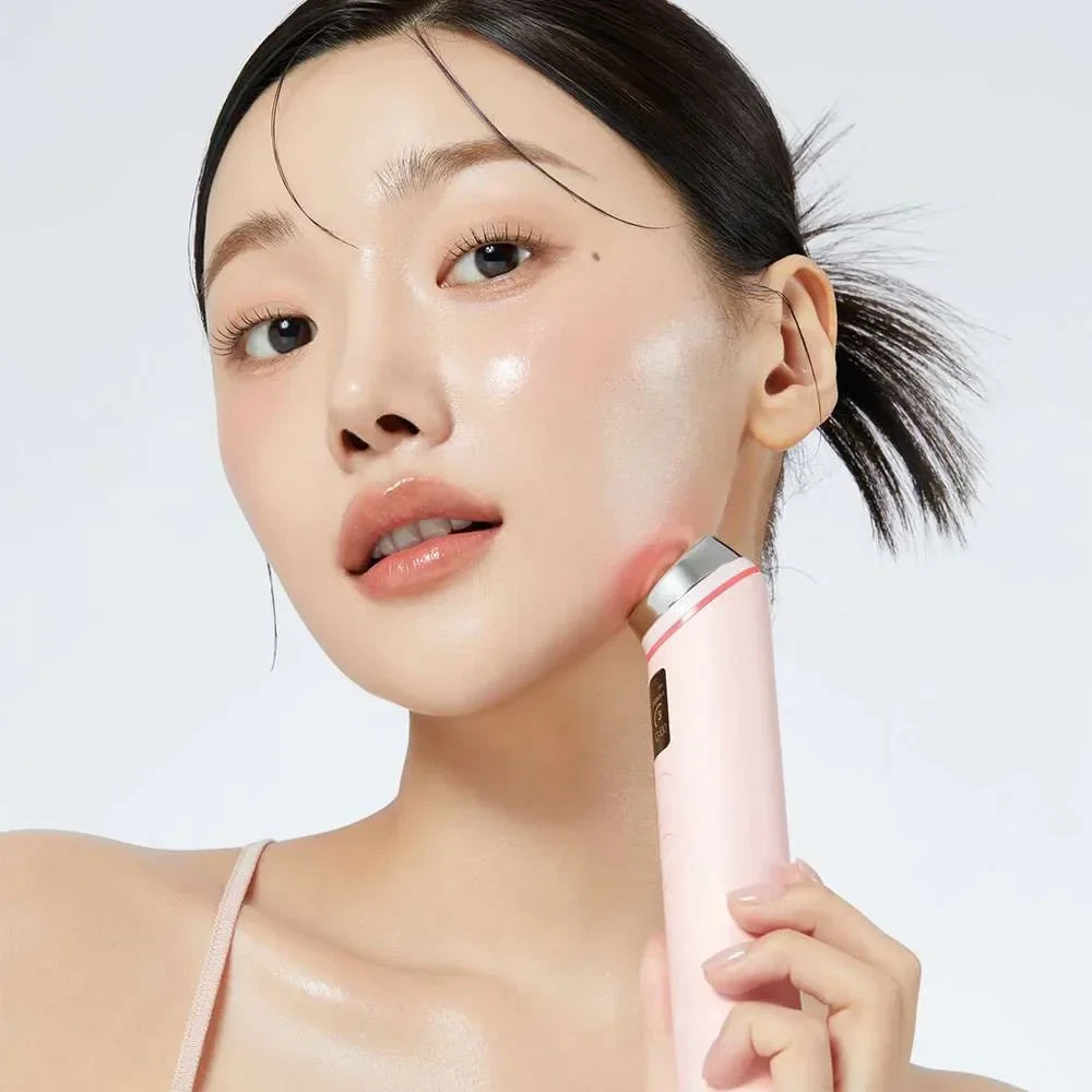 Model holding Medicube Age-R Booster Pro Pink device to her cheek