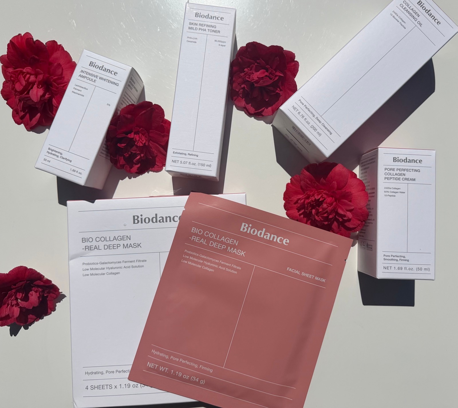 Biodance K-beauty skincare product collection including Bio-Collagen Real Deep Mask, Ampoule, Toner, Cleansing Oil, and Peptide Cream with red peonies