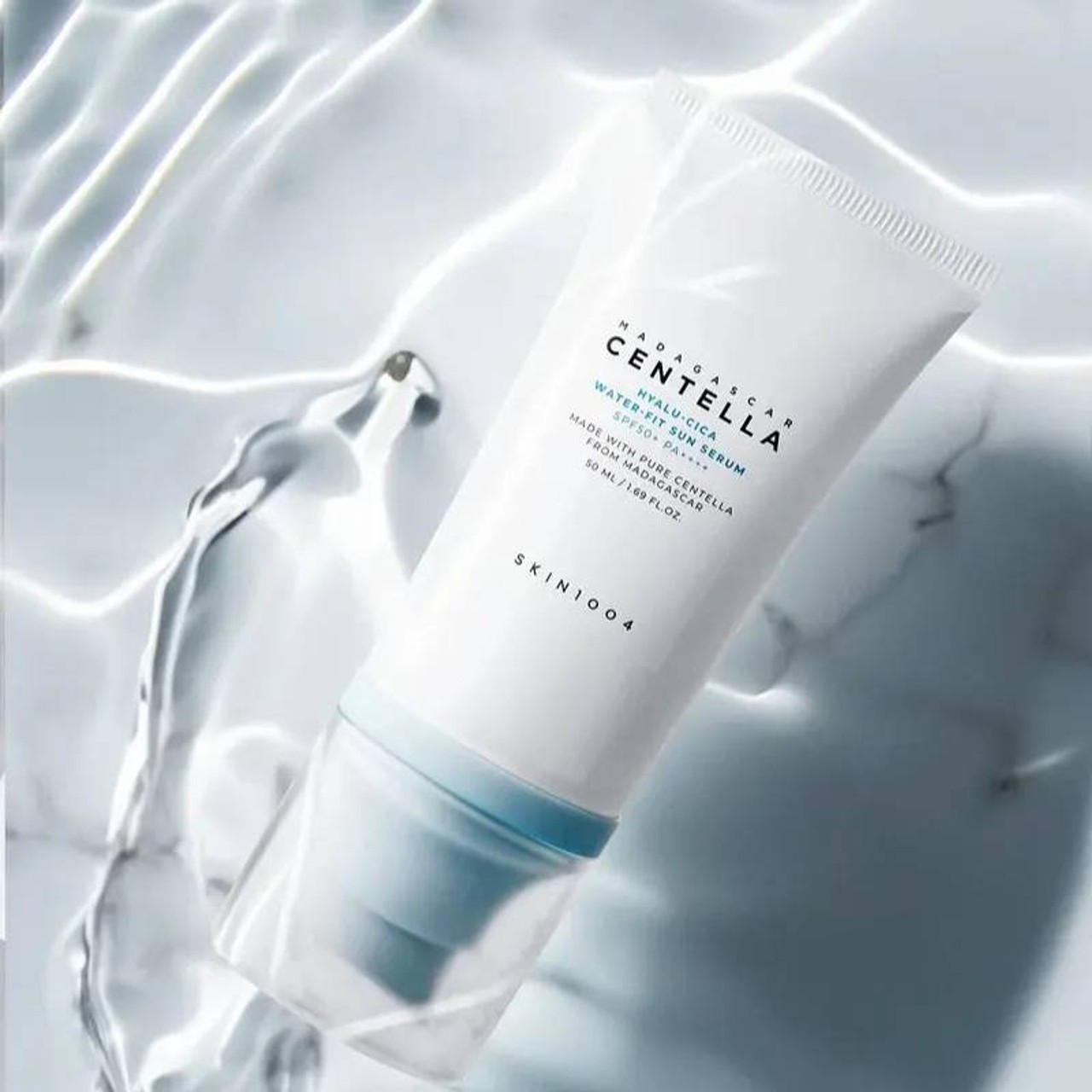 Skin1004 Madagascar Centella Hyalu-Cica Water Fit Sun Serum lying in a white pool