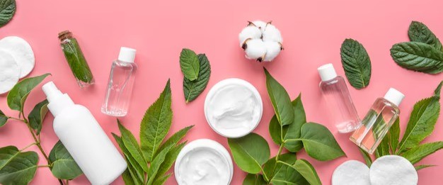 Skincare products on a bed of leaves and cotton flowers