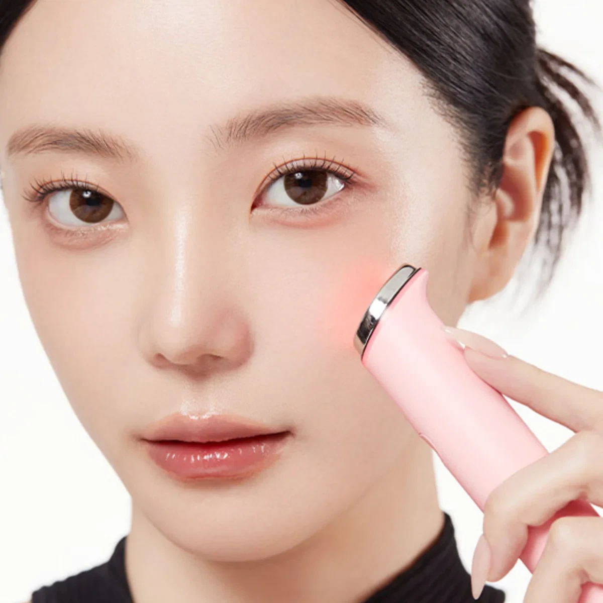 Medicube Age-R Booster Pro Mini pink being held to the cheek of a young woman
