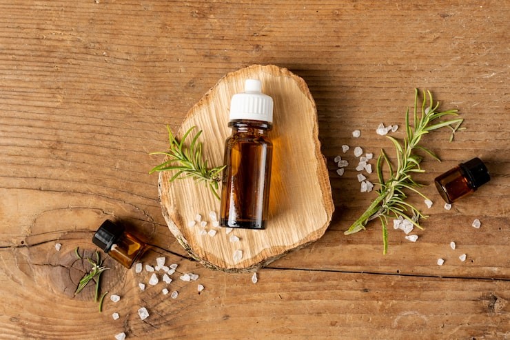 Essential oil bottles lying on a wooden base with rosemary and sea salt
