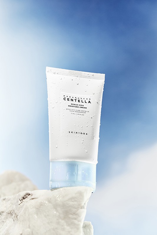 Skin1004 Madagascar Centella Hyalu-Cica Moisture Cream covered in water droplets and standing proudly on a white rock