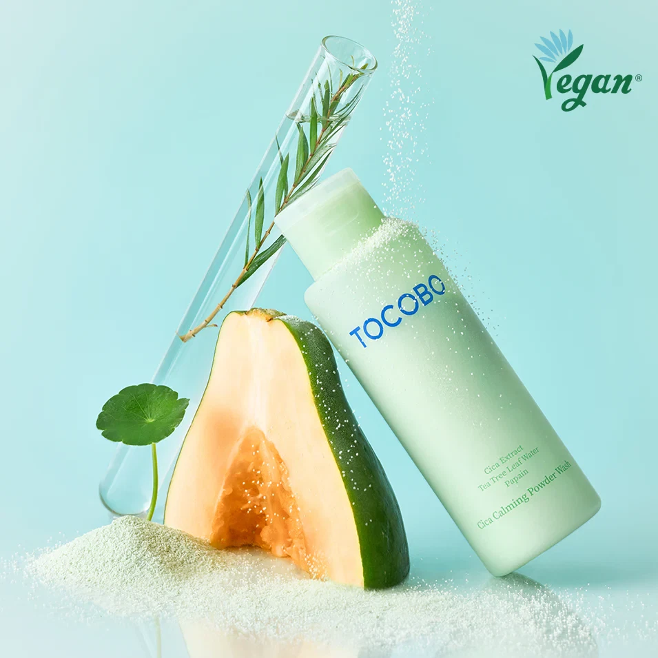 Tocobo Cica Cleansing Powder on a bed of green, light powder and next to a papaya