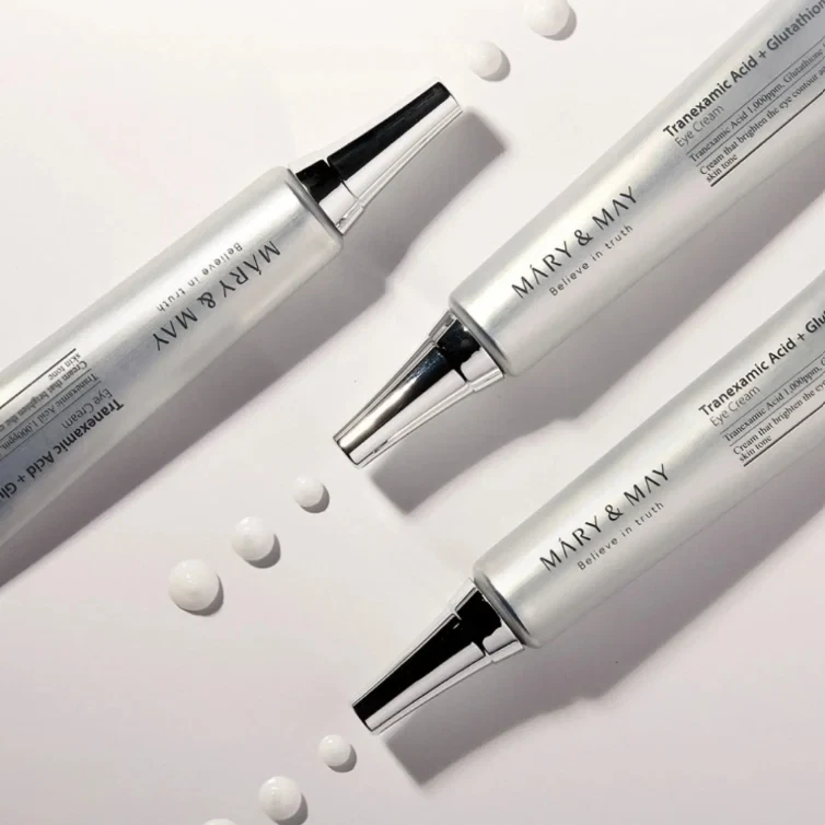 Mary and May Tranexamic Acid + Glutathione Eye Cream lying on white backgroudn with small droplets of cream
