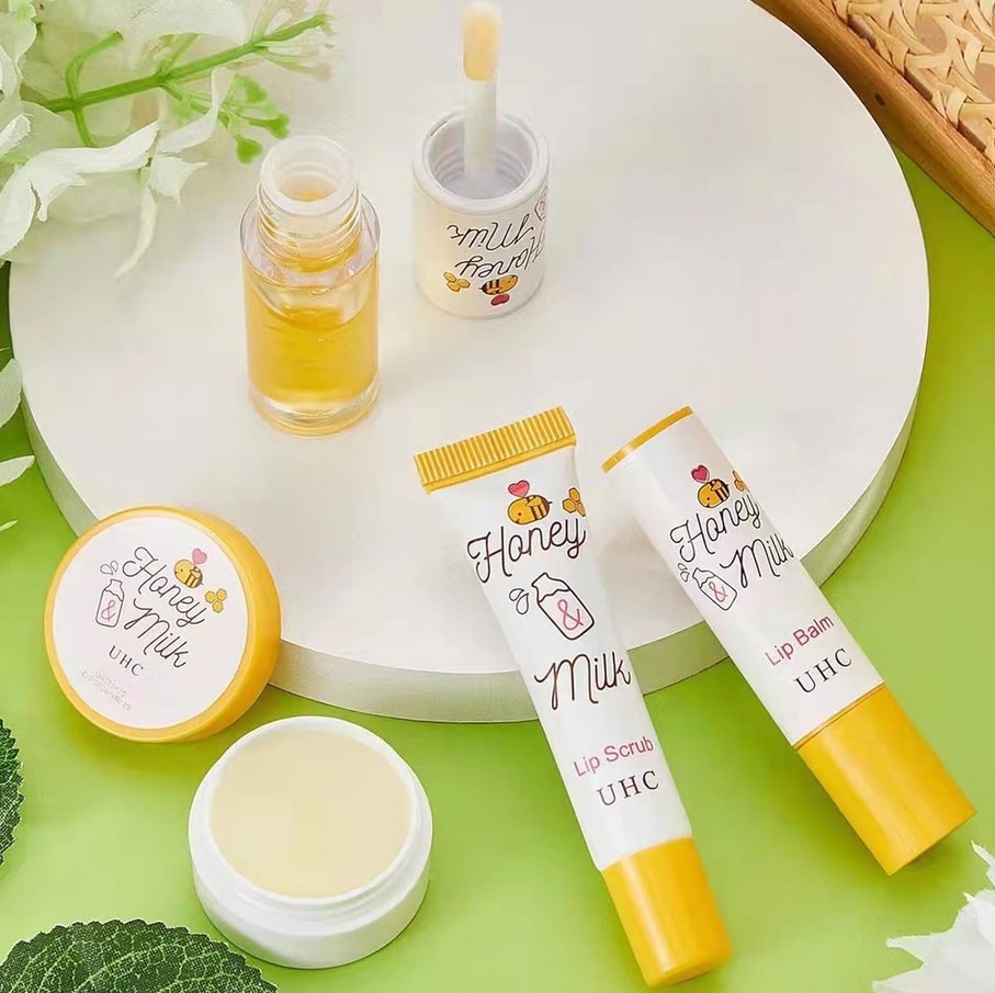 A’pieu Honey and Milk Lip Scrub set sitting on white table with honey and white flowers