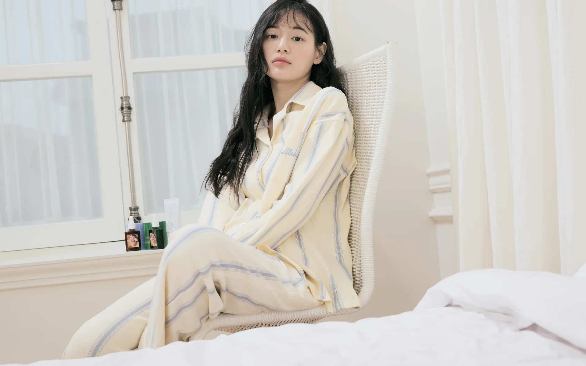 Dr Althea Founder Evelyn Lee sitting in a white chair with a white, blue striped suit