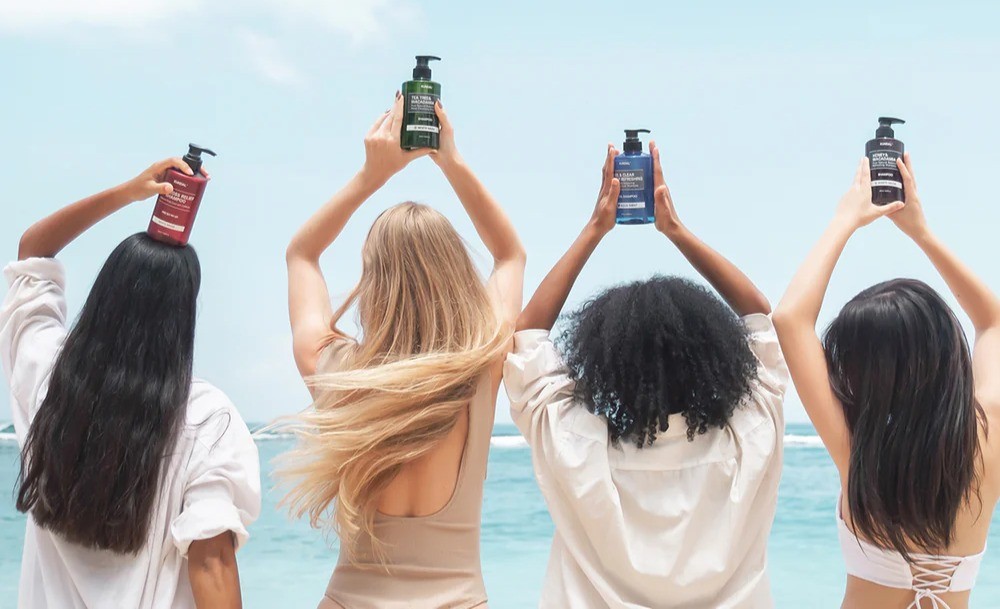 Models holding Kundal Hair Products above their head at the beach