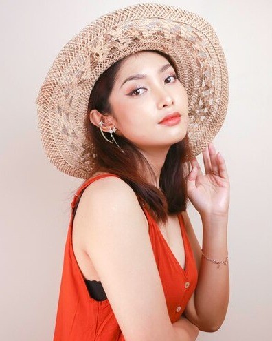 Young woman posing with straw hat and orange-red blouse