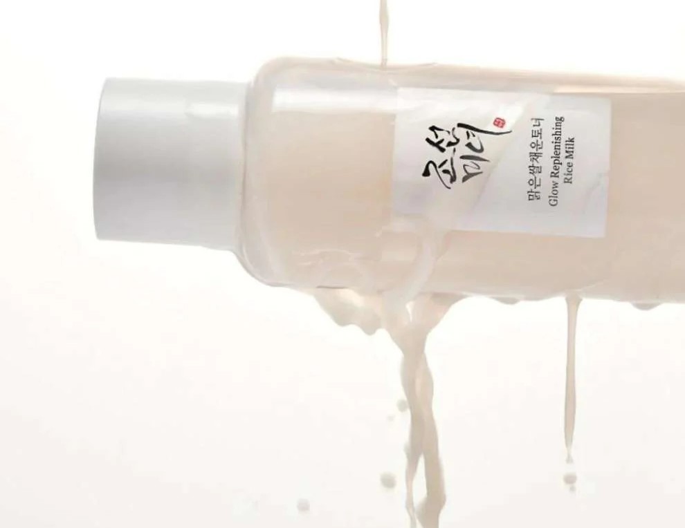 Beauty of Joseon Glow Replenishing Rice Milk toner held sideways and being soaked in rice milk toner, causing a gentle splash.