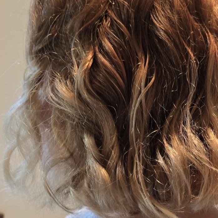Hair after protein treatment showing more closely bunched, blonde curls, with reduced frizziness