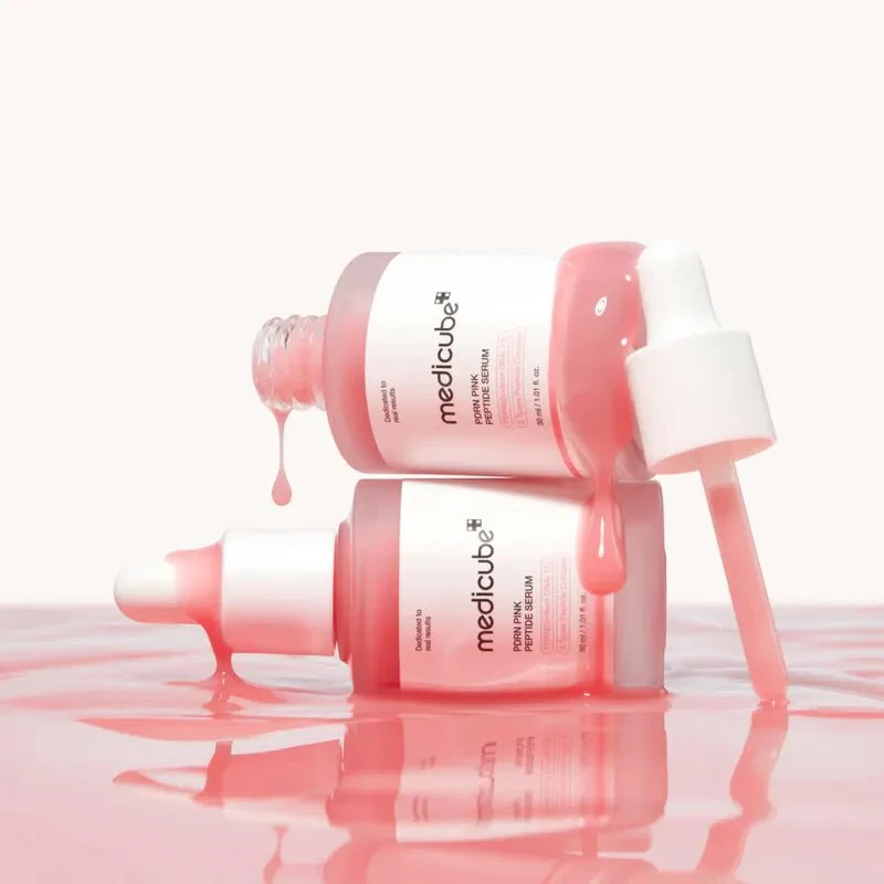 Medicube PDRN Pink Peptide Serum bottles lying in a river of serum