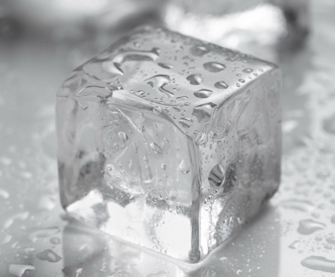 Grey-toned ice cube on a water droplet surface