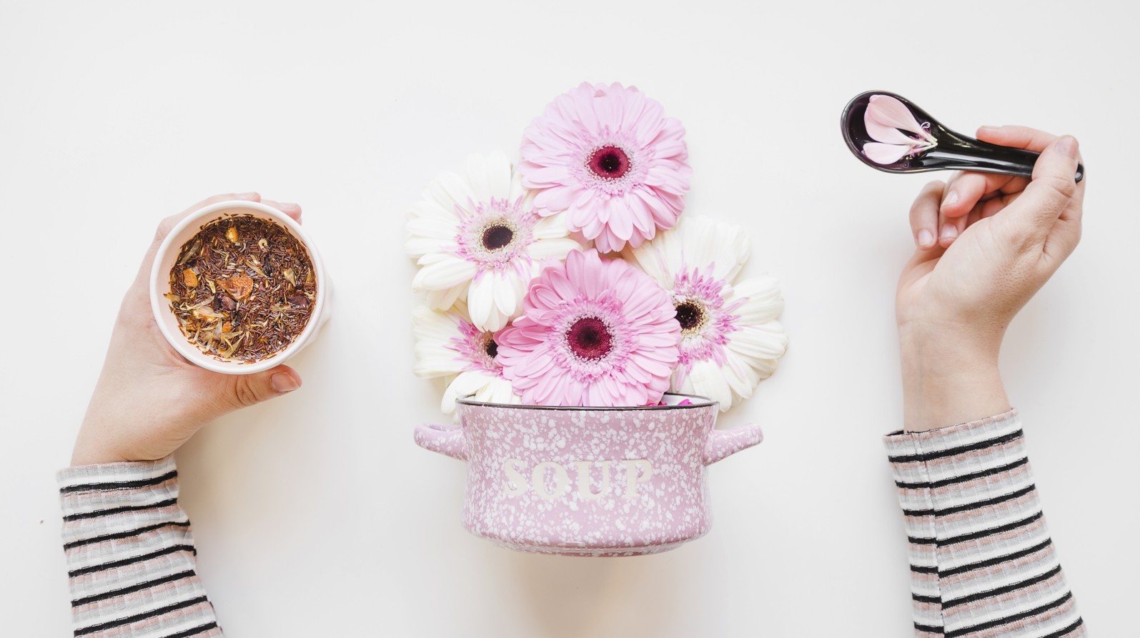 A pot of bright pink flowers with a pot-pourri mix and spoon full of petals
