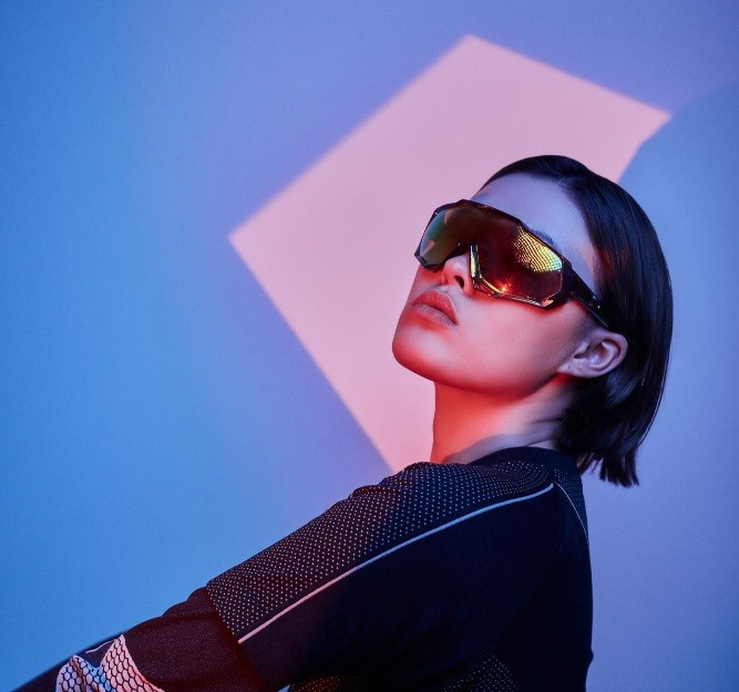 Futuristic Dressed Woman with cool sunglasses standing in purple lighting