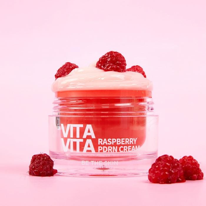 Be The Skin VitaVita Raspberry PDRN cream sitting in a pink background surrounded by red raspberries