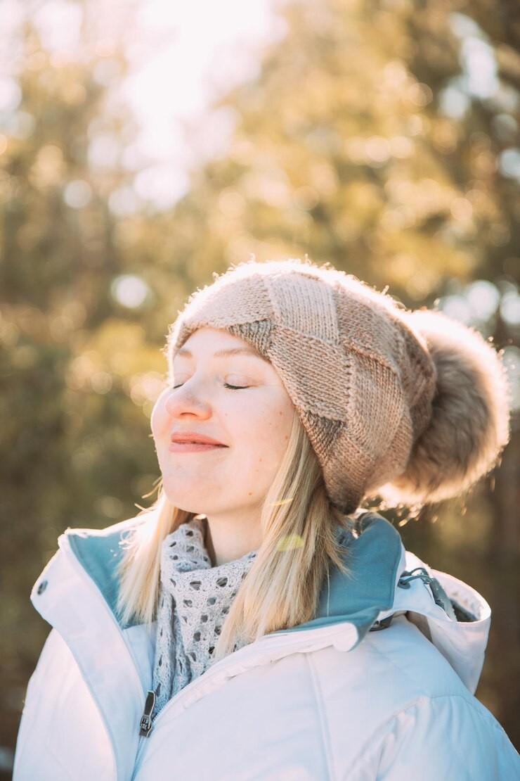 Winter tone - woman standing in winter setting with brown beanie and blue puffer jacket