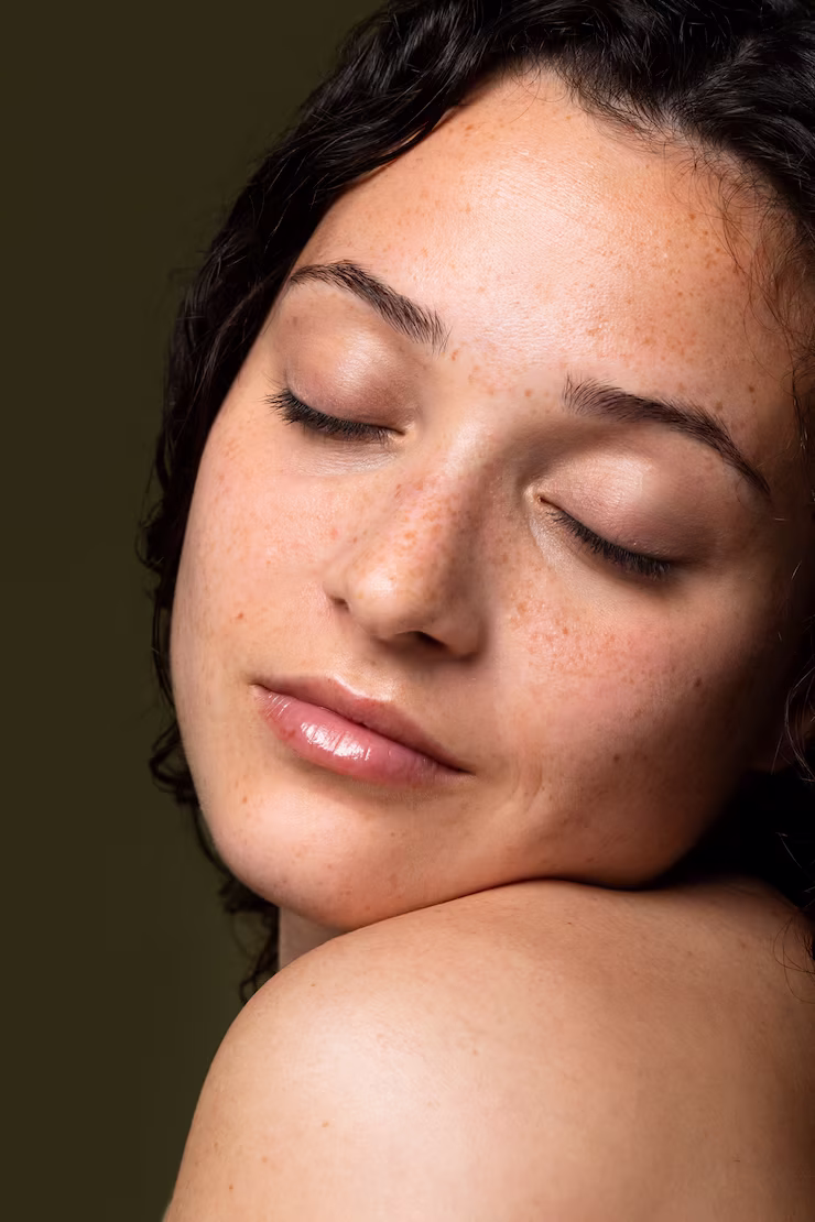 Woman posing in dark light with warm, bronze freckles