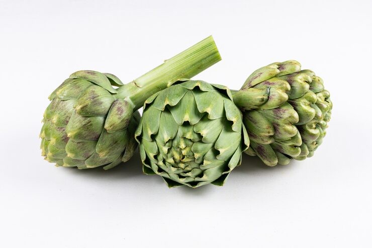 Trio of artichoke heads resting in a plain background