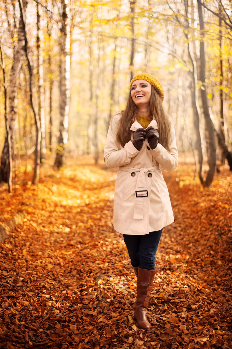 Woman standing in autumn forest surrounded by orange leaves