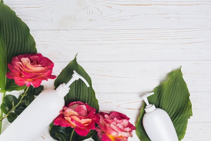Skincare white bottles surrounded by leaves and dark pink roses