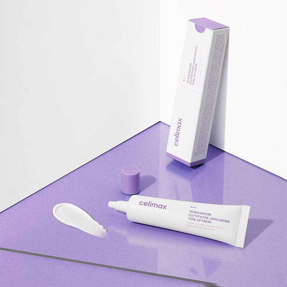 Celimax Tone-Up Glutathione Cream lying on purple, shiny benchtop with matching purple and white box next to it