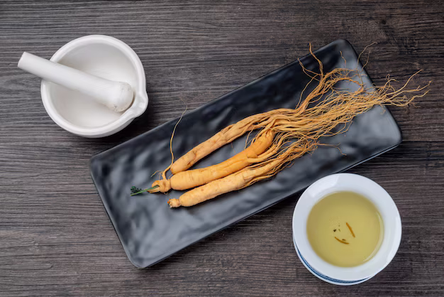 Tray of ginseng roots next to a mortar and pestle and a bowl of oil