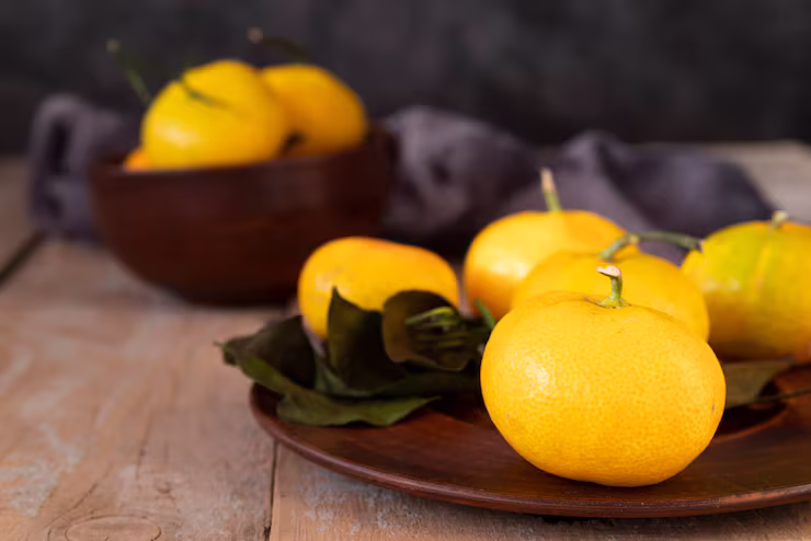 Bright yellow yuzu fruits sitting on a dark oak platter