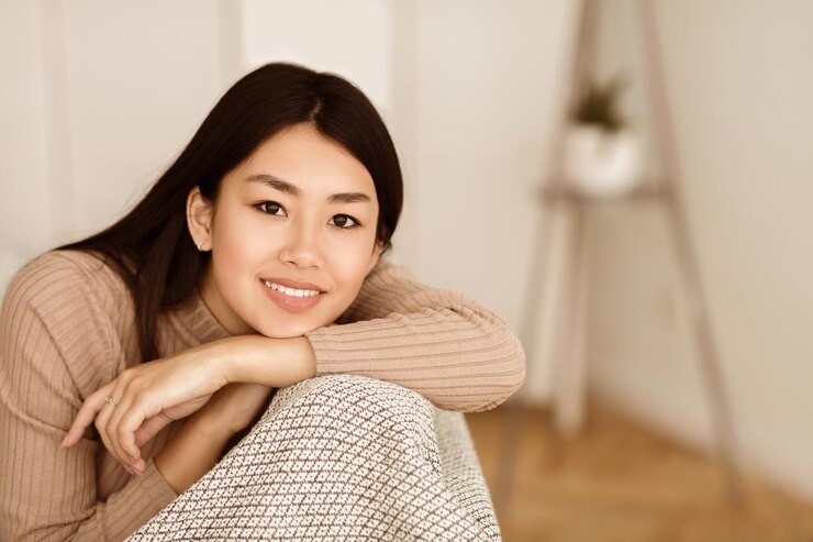 Woman smiling, dark eyes and soft-beige skin tone