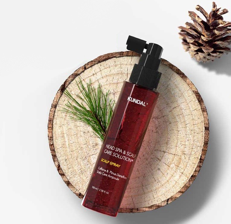Kundal Head Spa & Scalp Care + Scalp Tonic on a cut pine log