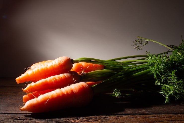 A fresh bundle of carrots sitting on a wooden countertop