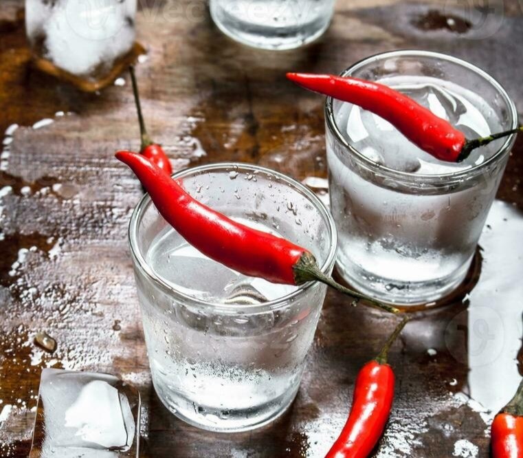 Shots of frosted water with ice cubes and bright red chilli on top