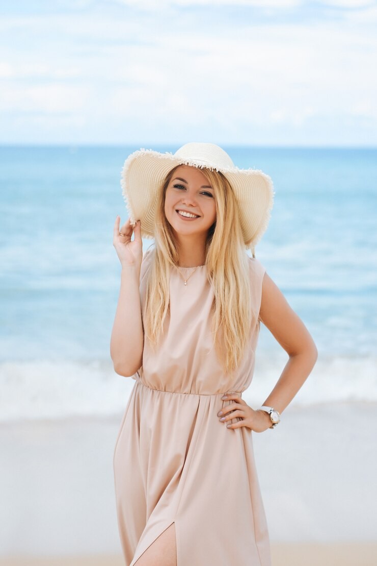 Woman standing at beach in bright summer with straw hat