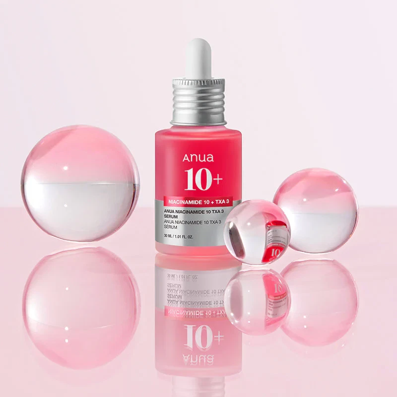 Anua’s Niacinamide 10% + TXA 4% serum in pink background with reflective glass balls