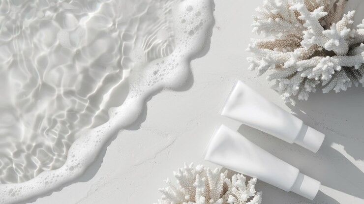 Cleanser bottles lying on white beach with coral