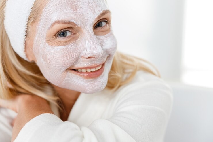 Elegant, older woman in white dressing gown with white facemask covering face