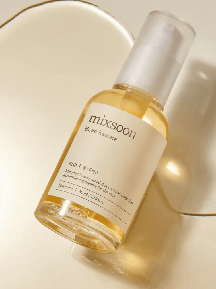 Mixsoon Bean Essence Serum sitting in a pool of clear, golden serum on a white background.