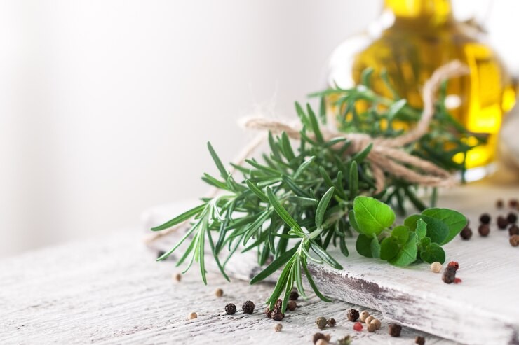 Rosermary, basil and bundled herbs sitting in front of olive oil on an ash wood surface