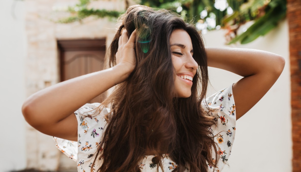 Woman with waves of brunette hair smiling in the sunshine