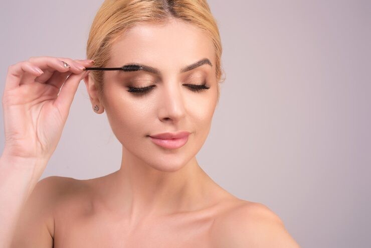 Woman applying eyebrow tint whilst posing slightly