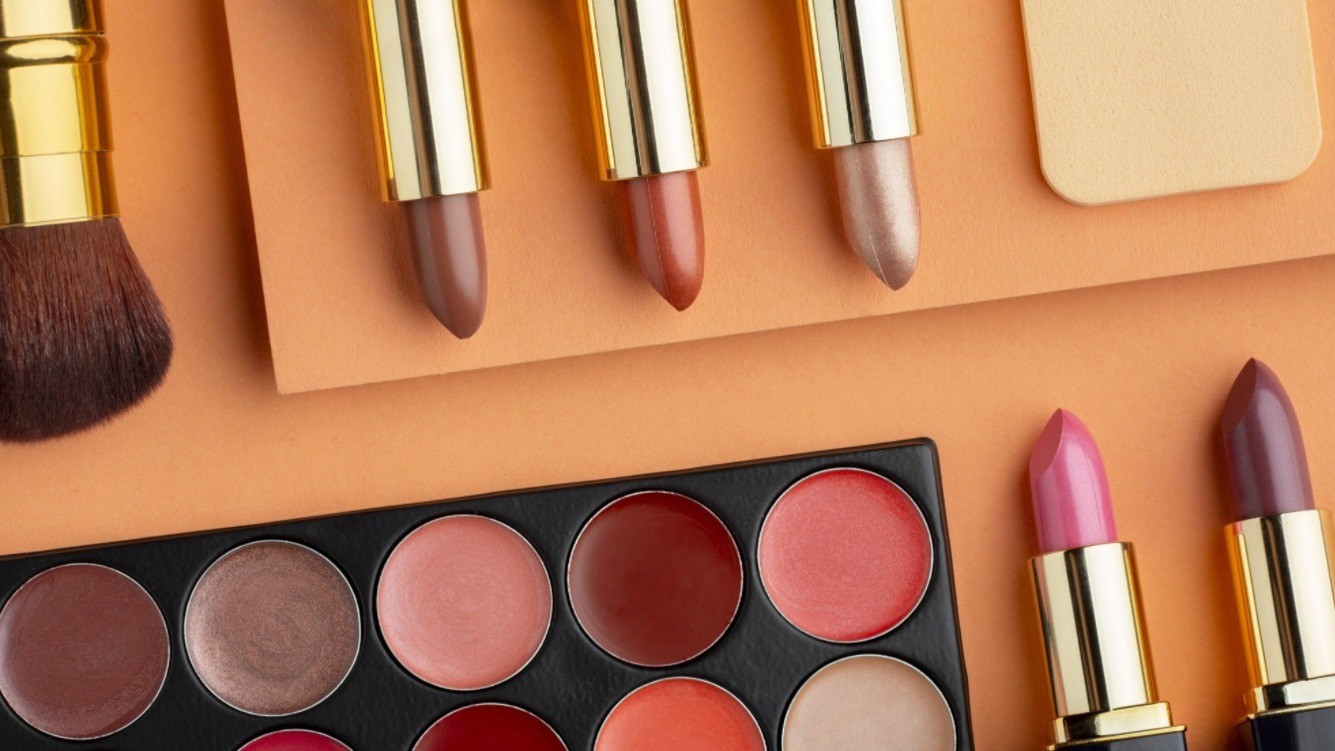 Eyeshadow palette and various shades of lipstick on a golden background