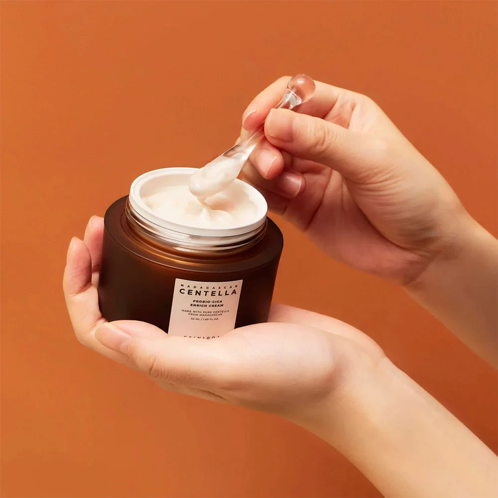 Skin1004 Madagascar Centella Probio-CIca Enrich Cream being held and being scooped out of jar