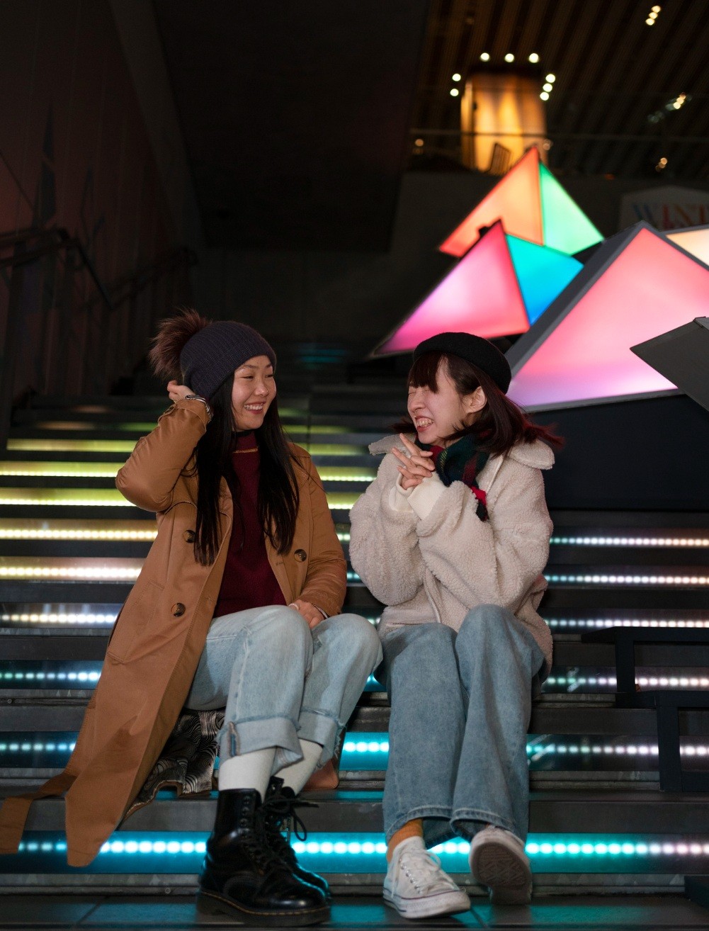 Two friends sitting on the steps of a city at night