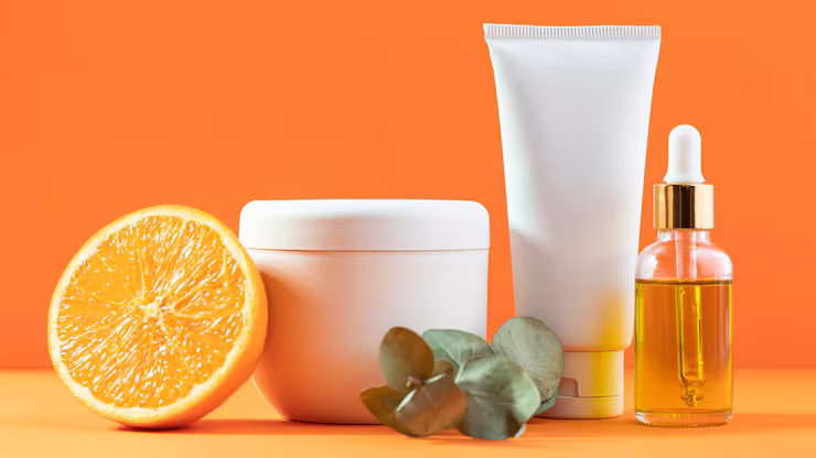 Brightening skincare products with a fresh cut orange posed in a summery background