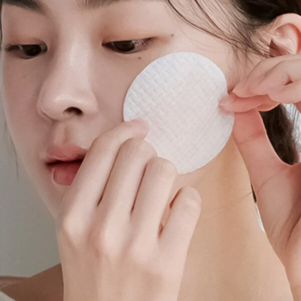 Model using Celimax Ji Woo Gae Cica BHA Blemish Toner Pad on her cheek
